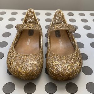 Mini Melissa camps a gold glitter shoes